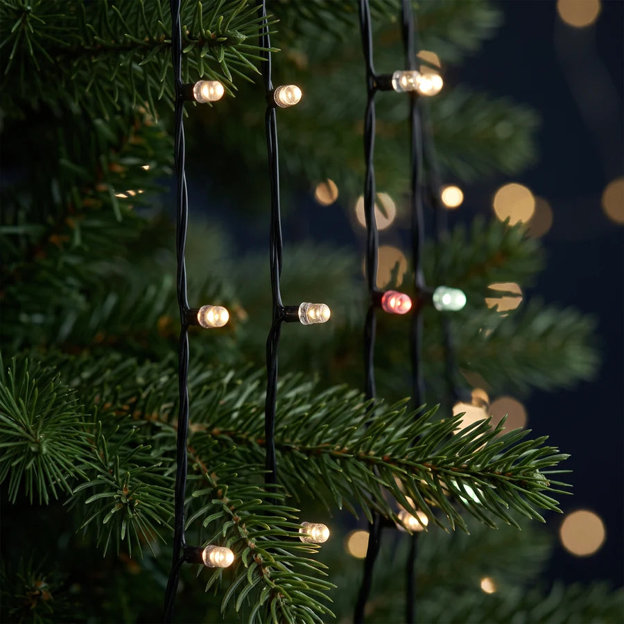 A close look at individual LED pixels glowing among Christmas tree branches